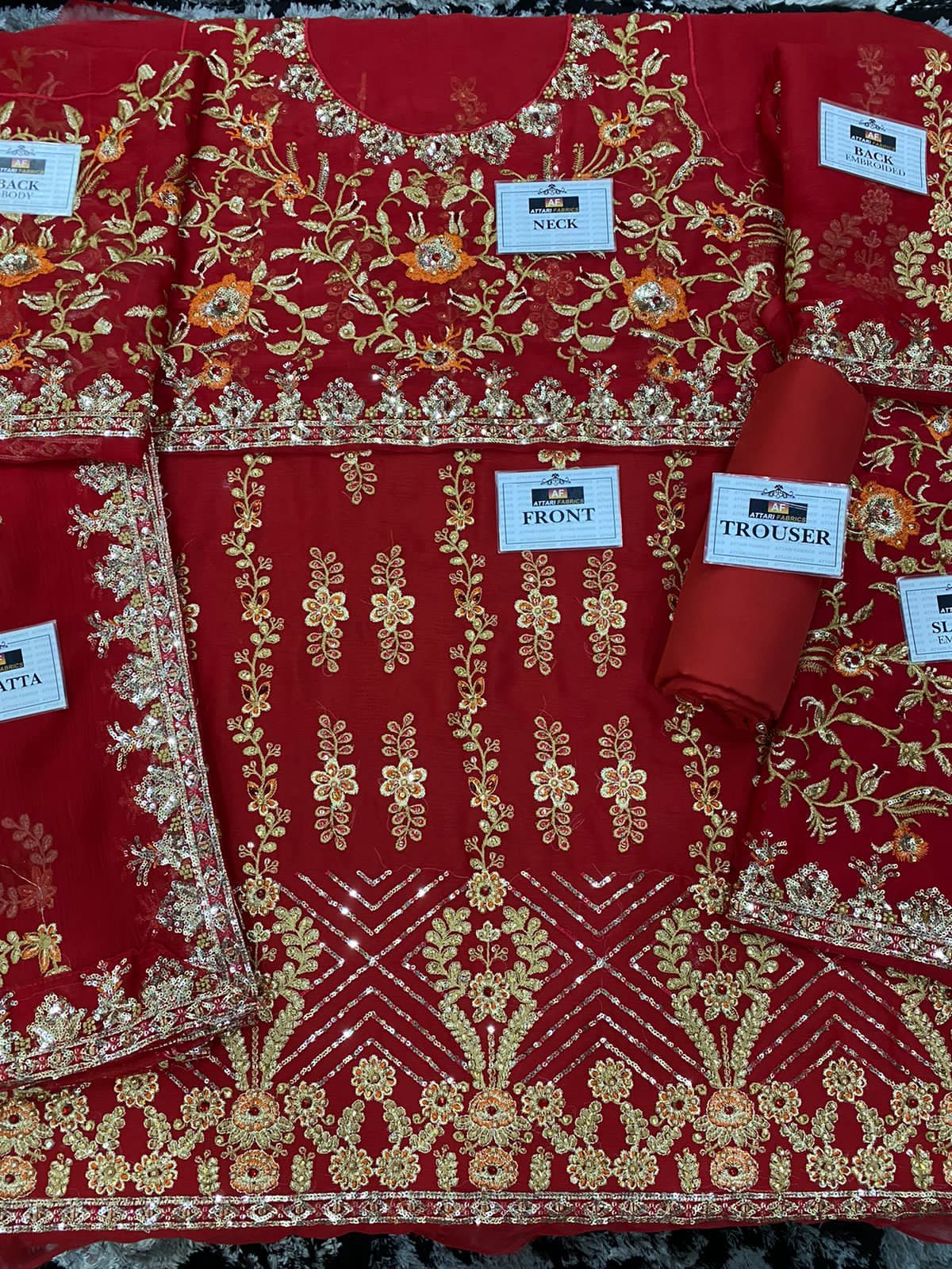 Red embroidered garment with gold patterns, labeled as front, trouser, and sari.