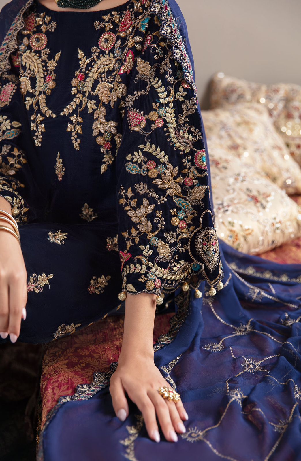 Emaan Adeel Navy blue embroidered traditional outfit with gold patterns, sitting on a textured surface.