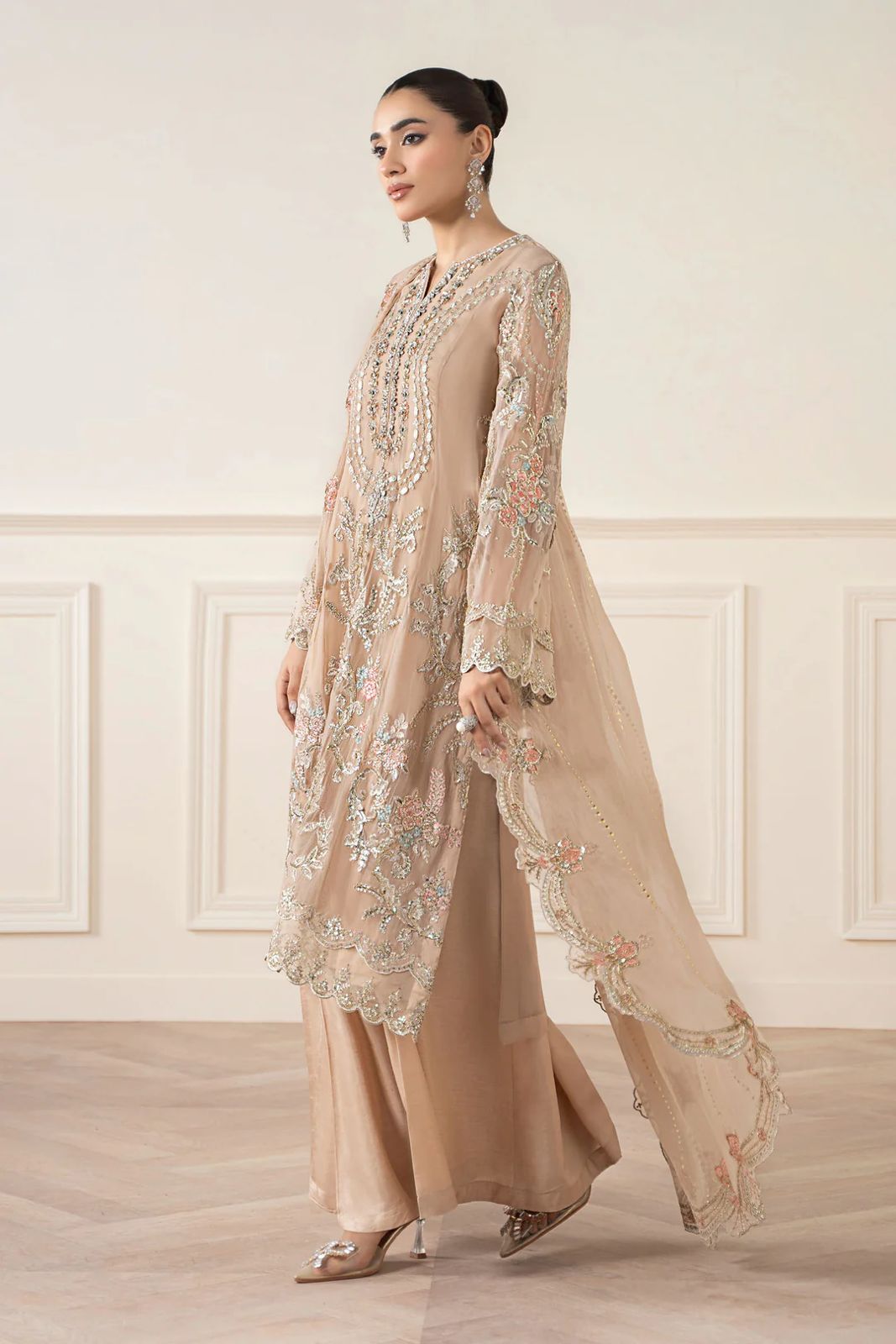 Maria b Formal & Wedding Woman wearing a beige embroidered outfit in a room with white walls and wooden floor.