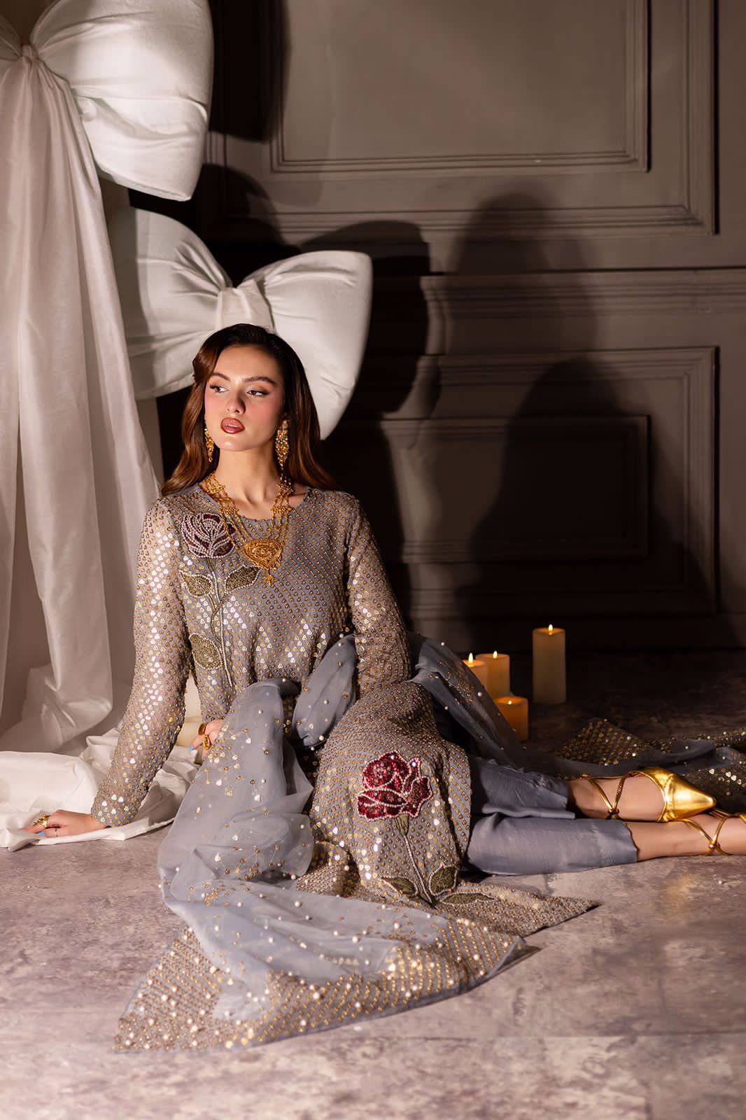Nure Midnight Wedding & paRTY wEAR Woman in a sparkling outfit sitting on a textured surface with candles and decorative elements.