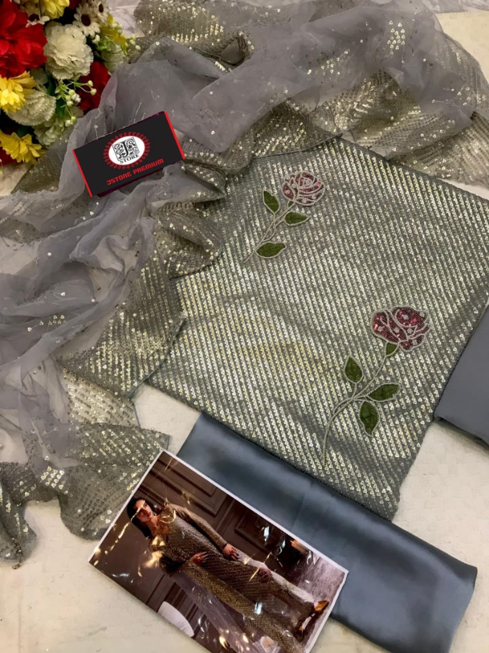Embroidered fabric with floral patterns on a table, next to a sheer fabric and a box.
