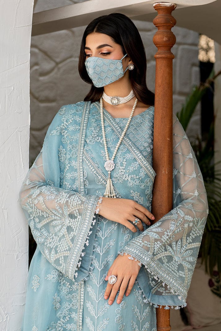 Flossie Blossom Sky Dress in a light blue embroidered traditional outfit standing in an outdoor setting.