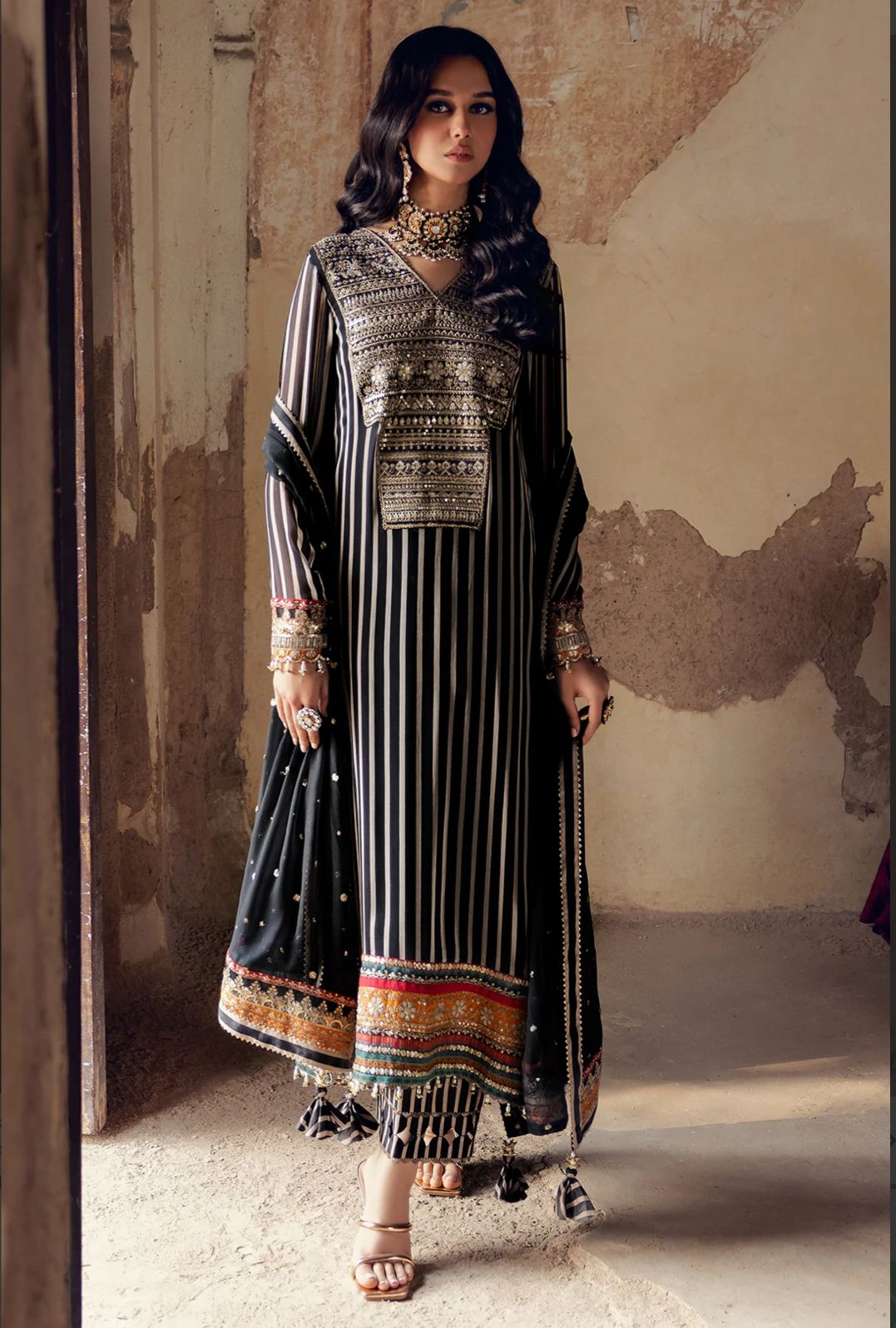 Charizma Luxury Chiffon Printed Black PAkistani Dress 2025 Woman wearing a traditional outfit with intricate patterns in a rustic setting