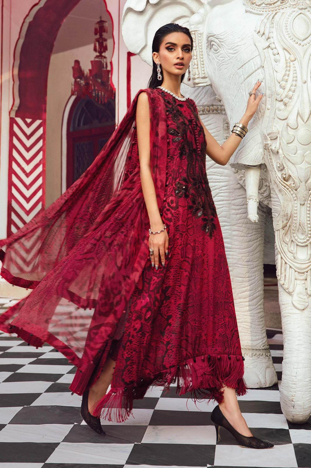 Maria b M print a red dress standing next to an elephant in a decorated setting