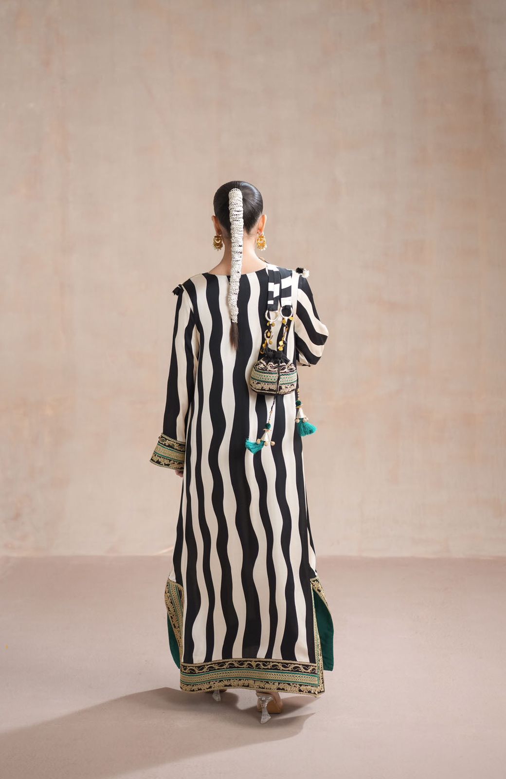 Woman wearing a black and white striped dress with green accents against a beige background