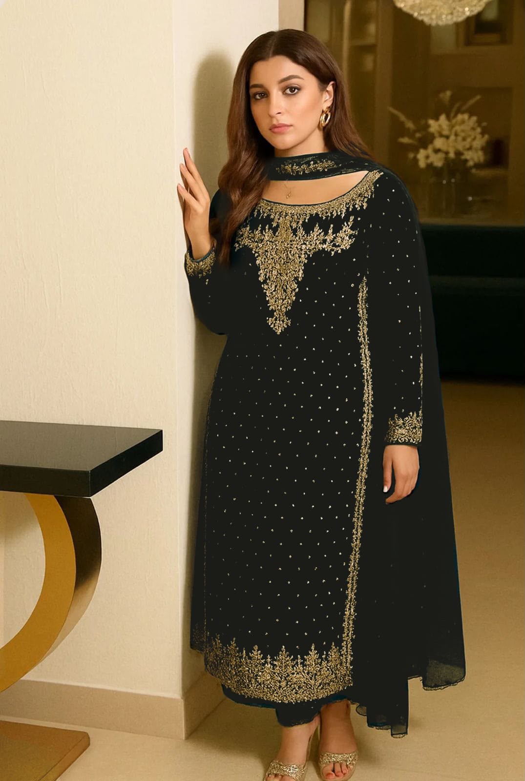 A woman modeling a black long kurta with gold embroidery and a matching sheer black dupatta in an indoor setting.