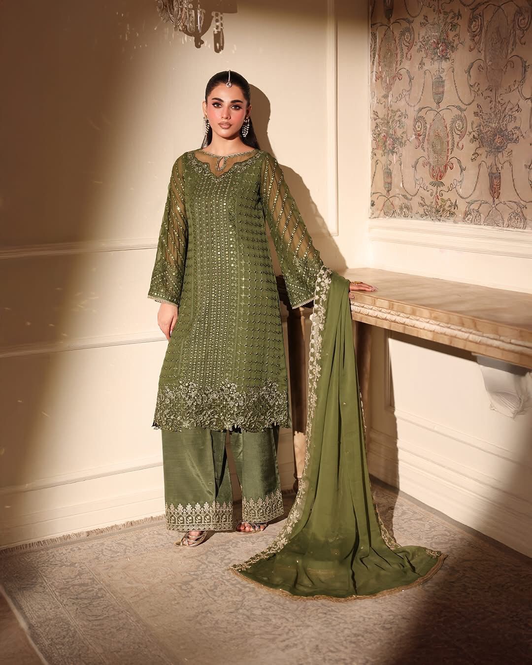 Azure Green Mehndi 9mm Sequence chiffon dressgreen embroidered traditional outfit standing in a decorated room.