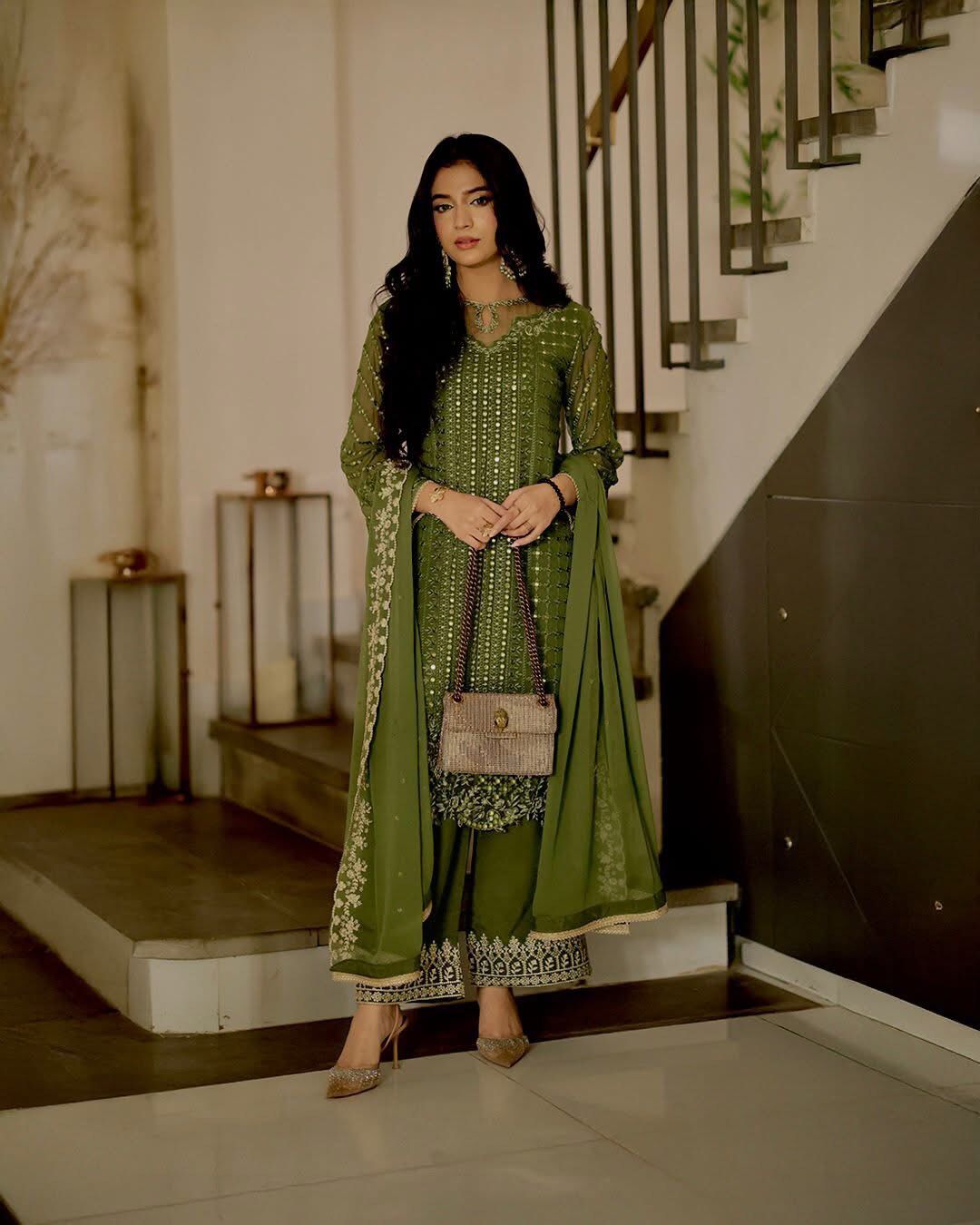 Laiba Khan green traditional outfit standing in a modern indoor setting.