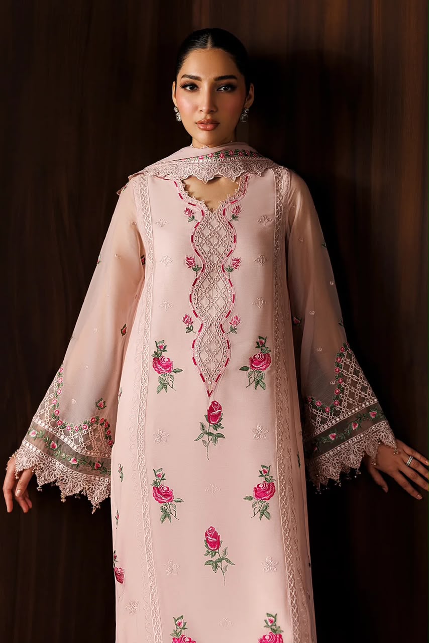 Woman wearing a light pink embroidered traditional outfit against a dark background