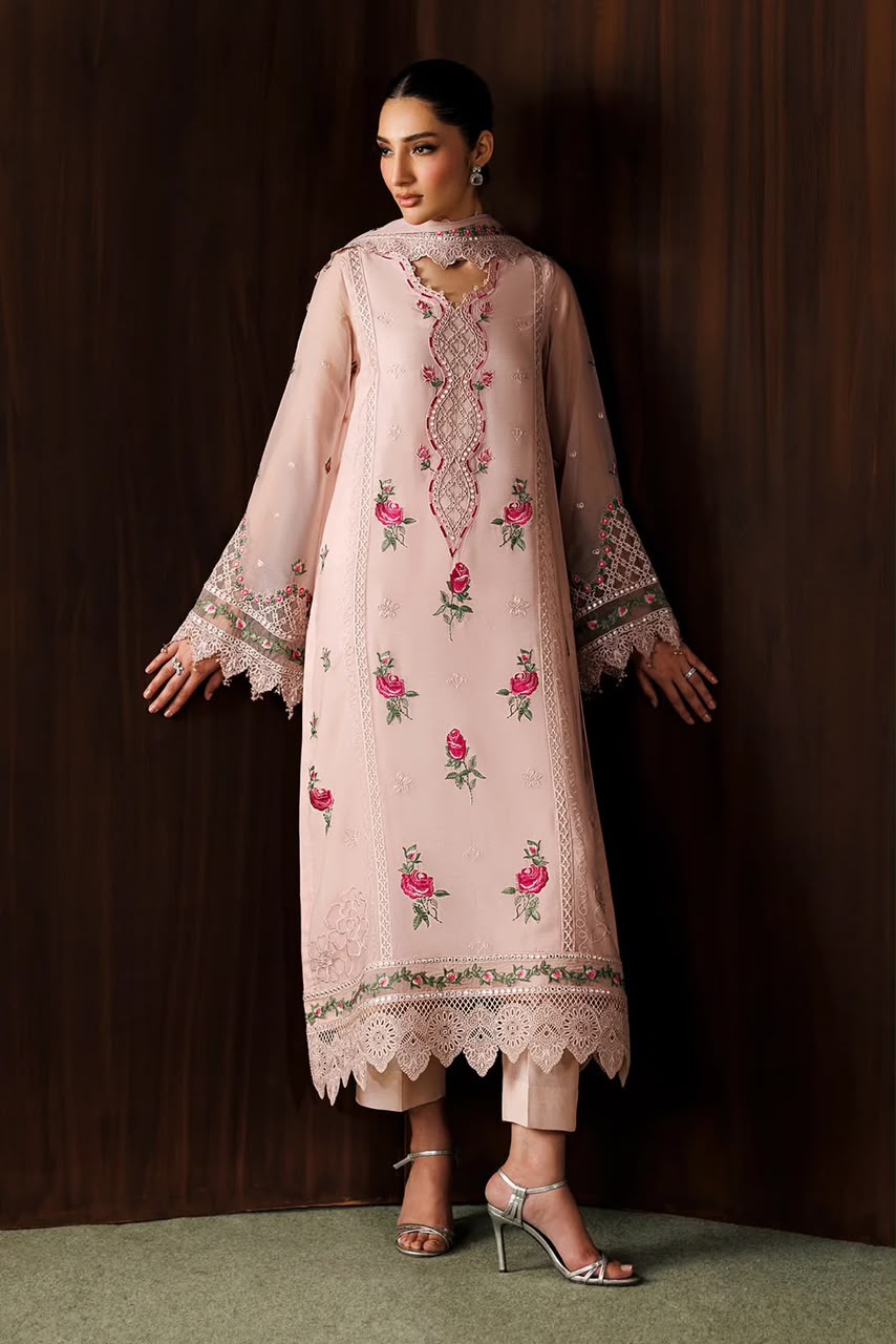Woman wearing a light pink embroidered dress against a dark background
