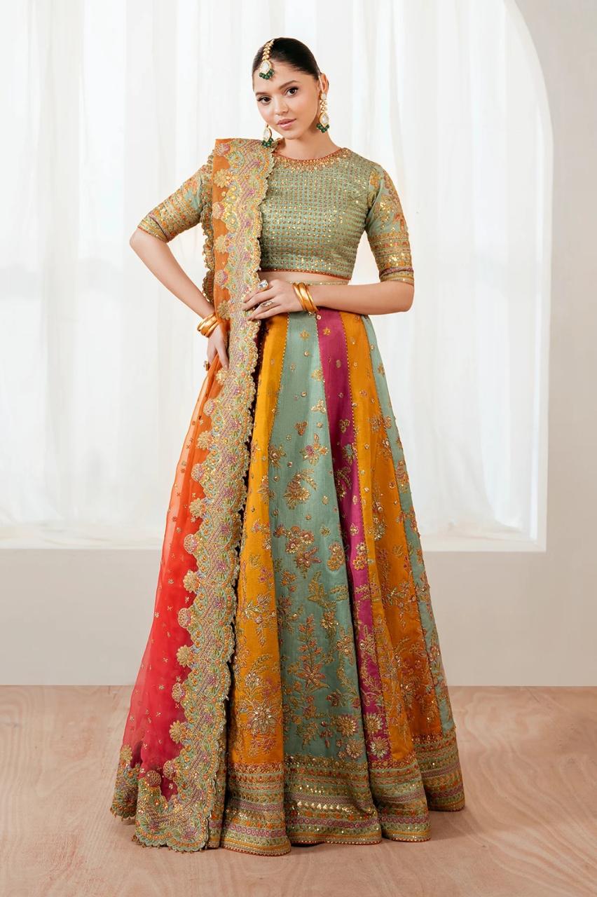 Woman wearing a traditional multicolored lehenga with a green blouse against a white curtain background