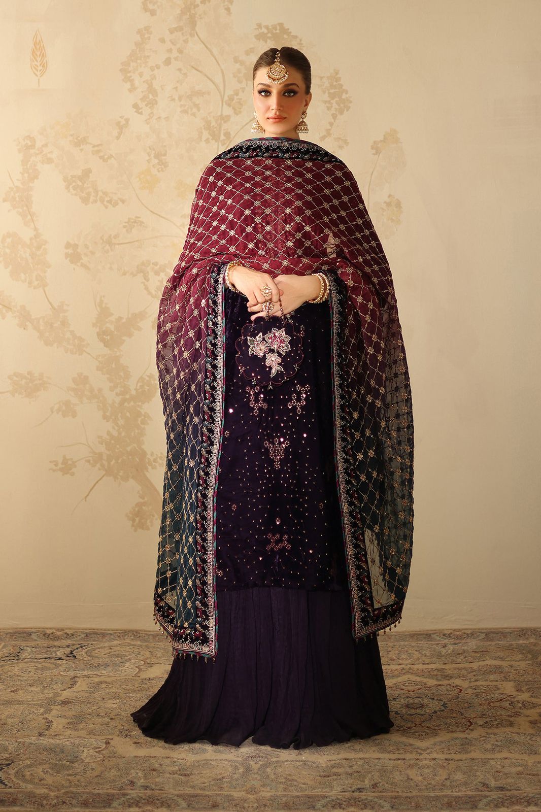 Woman wearing a dark purple traditional outfit with a matching shawl against a neutral background