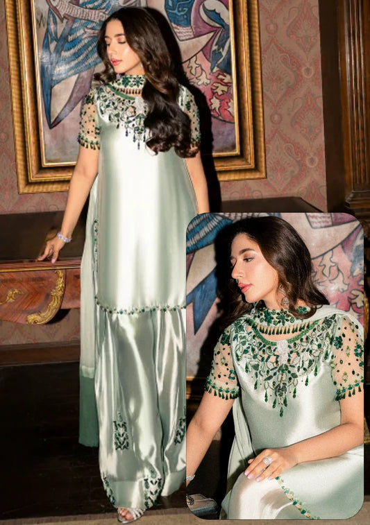 A woman modeling a light sage green satin three-piece traditional outfit with green and black embroidered details, shown in a full-length view and a close-up inset against an indoor background.