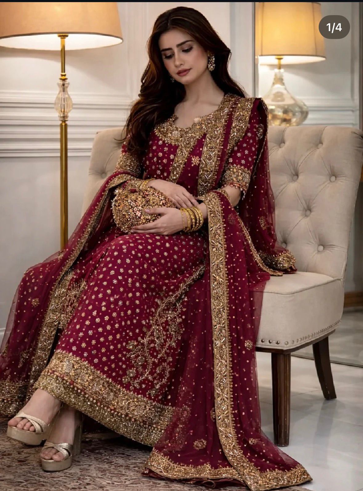 Woman in a maroon and gold traditional outfit sitting on a white chair.