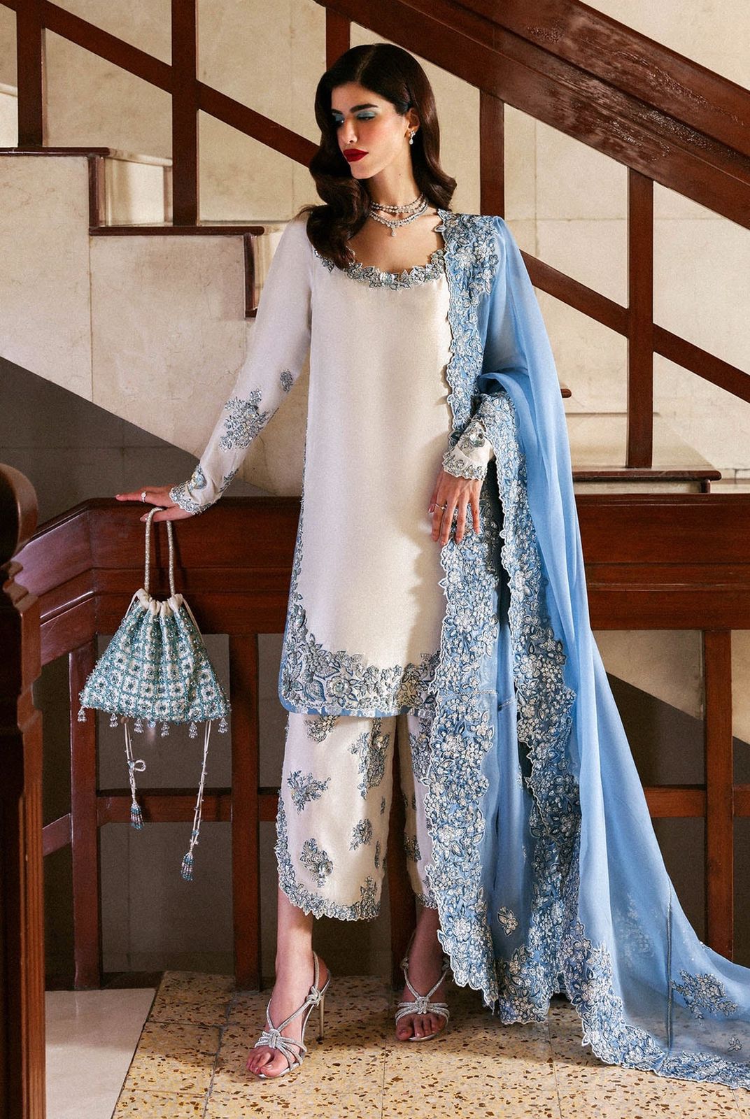 Hussain Rehar Wz-02 Sheesha Silk Heavy Adda Work With Clutch 2025l outfit with white and blue embroidered attire standing on a staircase.