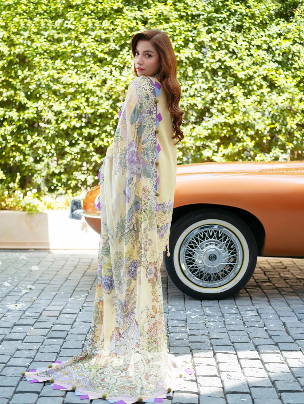Jade Ombre Purple Dananeer Lemon floral dress standing next to a vintage car with greenery in the background