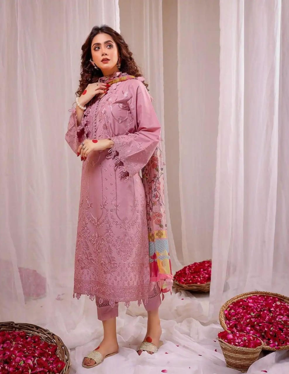 Limelight Dhanak Embroidered Dress Winterpink embroidered outfit standing in front of white curtains with rose petals on the floor.
