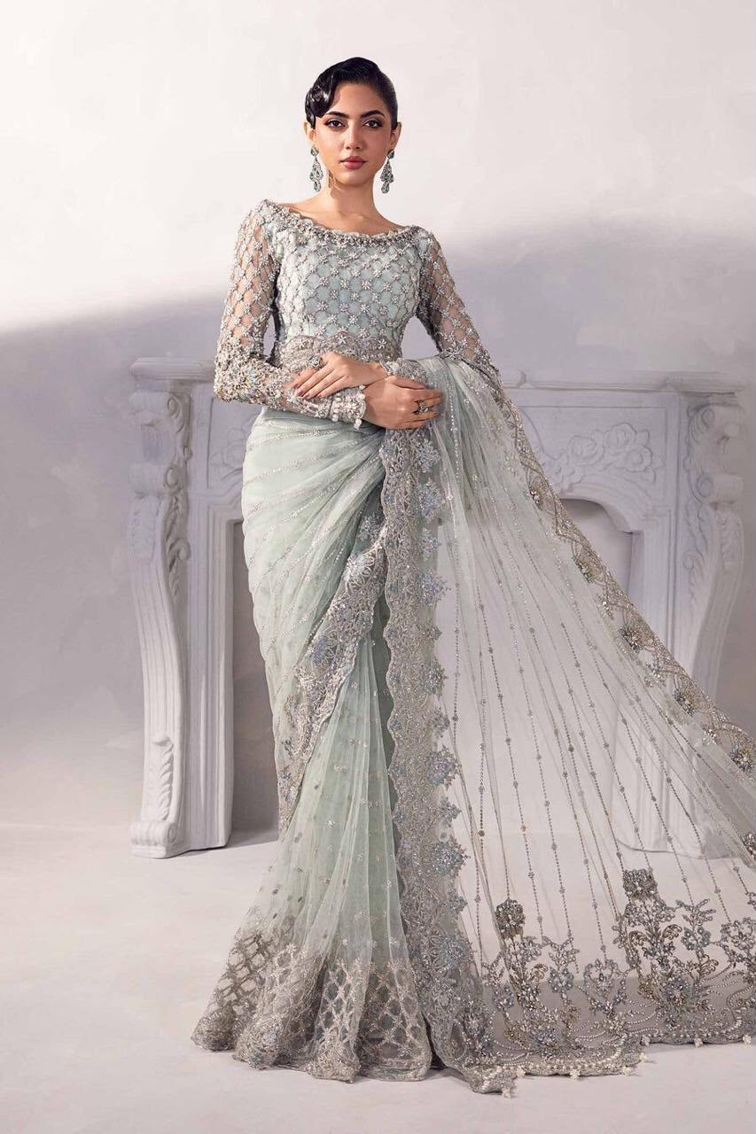 Woman wearing a light blue saree with silver embroidery against a white background