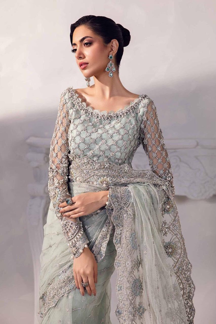 Woman wearing a light blue embroidered traditional outfit with a white background