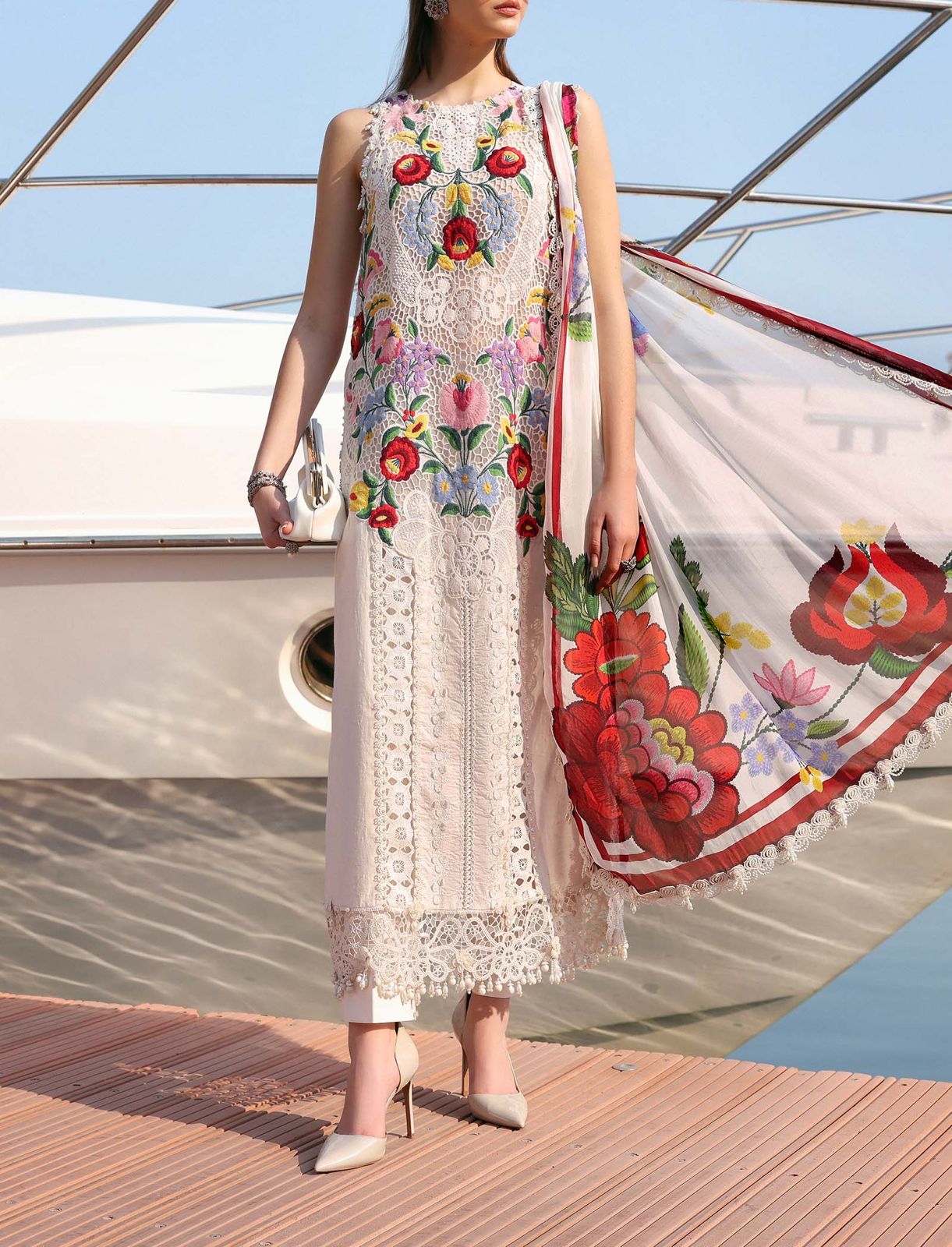 Woman in a floral dress standing on a boat with a colorful scarf.