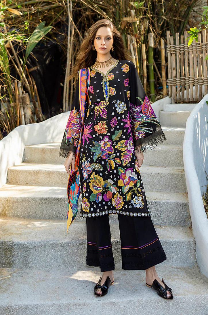 Woman in a black floral dress with colorful sleeves standing on stone steps outdoors.