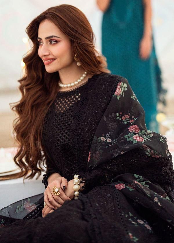 Nureh Black Sana Jawed embroidered outfit with floral patterns, sitting indoors.