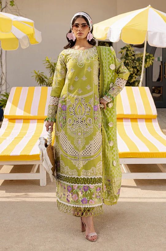 Woman in a green embroidered outfit standing in front of yellow and white striped chairs.