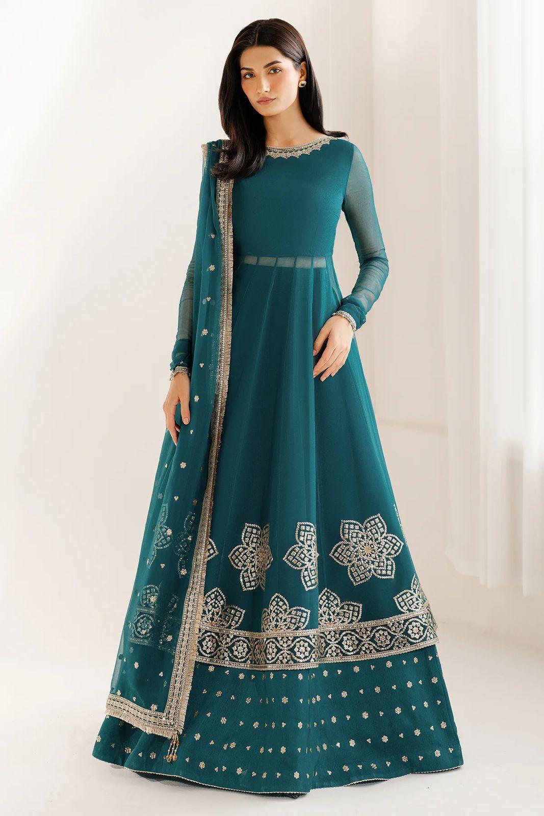 Woman wearing a teal anarkali suit with silver embroidery on a white background