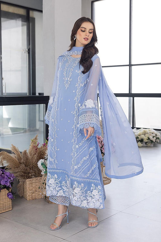 Woman wearing a light blue embroidered outfit in a modern indoor setting