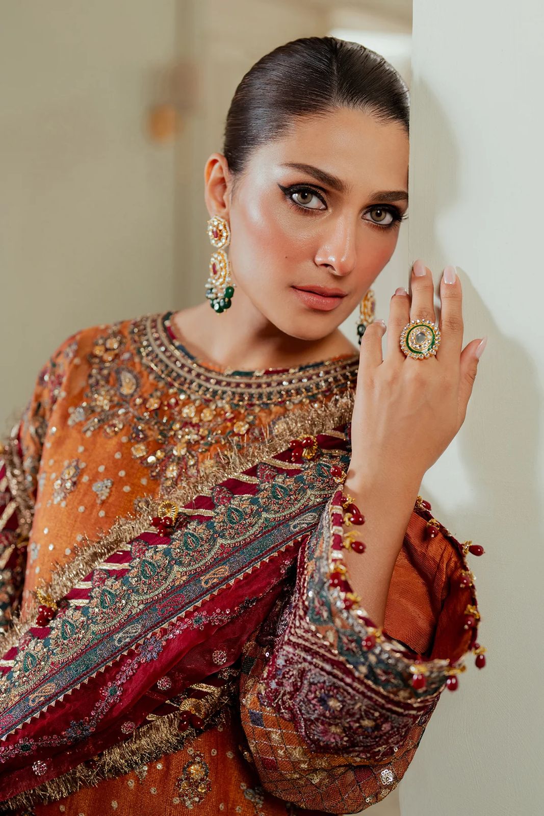 Jazmin Bridal Wear PAkistani Dress  Woman in traditional embroidered outfit with jewelry, posing indoors.
