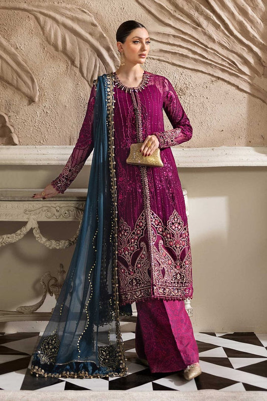MAria b Wedding & Party Wear Dress Woman in a traditional embroidered outfit with a blue dupatta against an ornate wall.