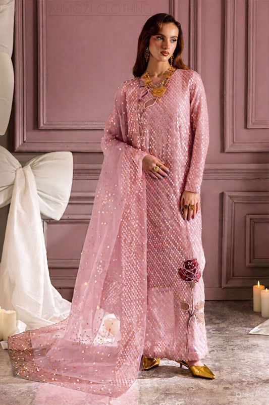 Nure Midnight Pink Wedding & PArty Wear Woman in a pink embroidered outfit standing in a decorated room with candles and a bow.
