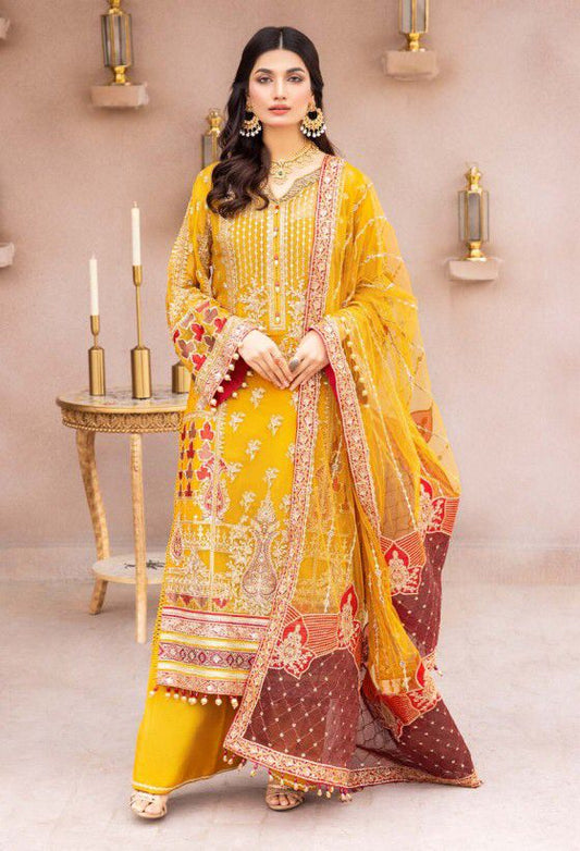 Adan Libas Woman in a yellow and red traditional outfit with intricate patterns, standing in a decorated room.
