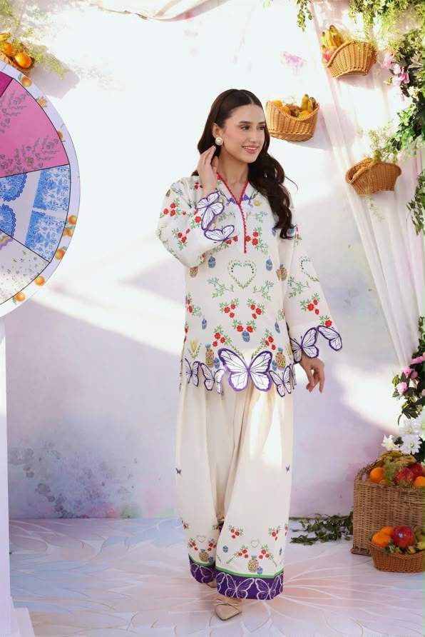 Woman wearing a floral dress with butterfly designs in a decorated indoor setting.