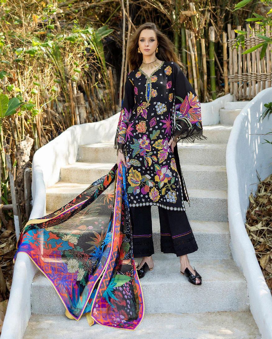 Woman in a black floral dress with colorful scarf standing on white steps outdoors.